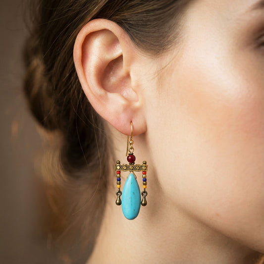 Close-up of an ear wearing a colorful earring with a turquoise drop.