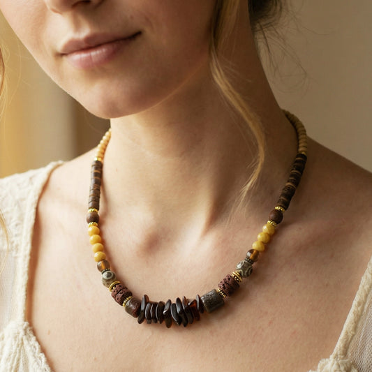 Close-up of a person wearing a beaded necklace with a neutral background