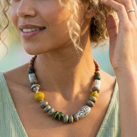 Woman wearing a beaded necklace with a blurred natural background