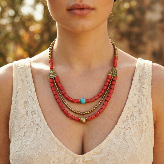 Necklace with red beads and gold accents worn by a person in a blurred outdoor setting