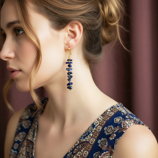 Close-up of a woman wearing blue beaded earrings with a patterned top.