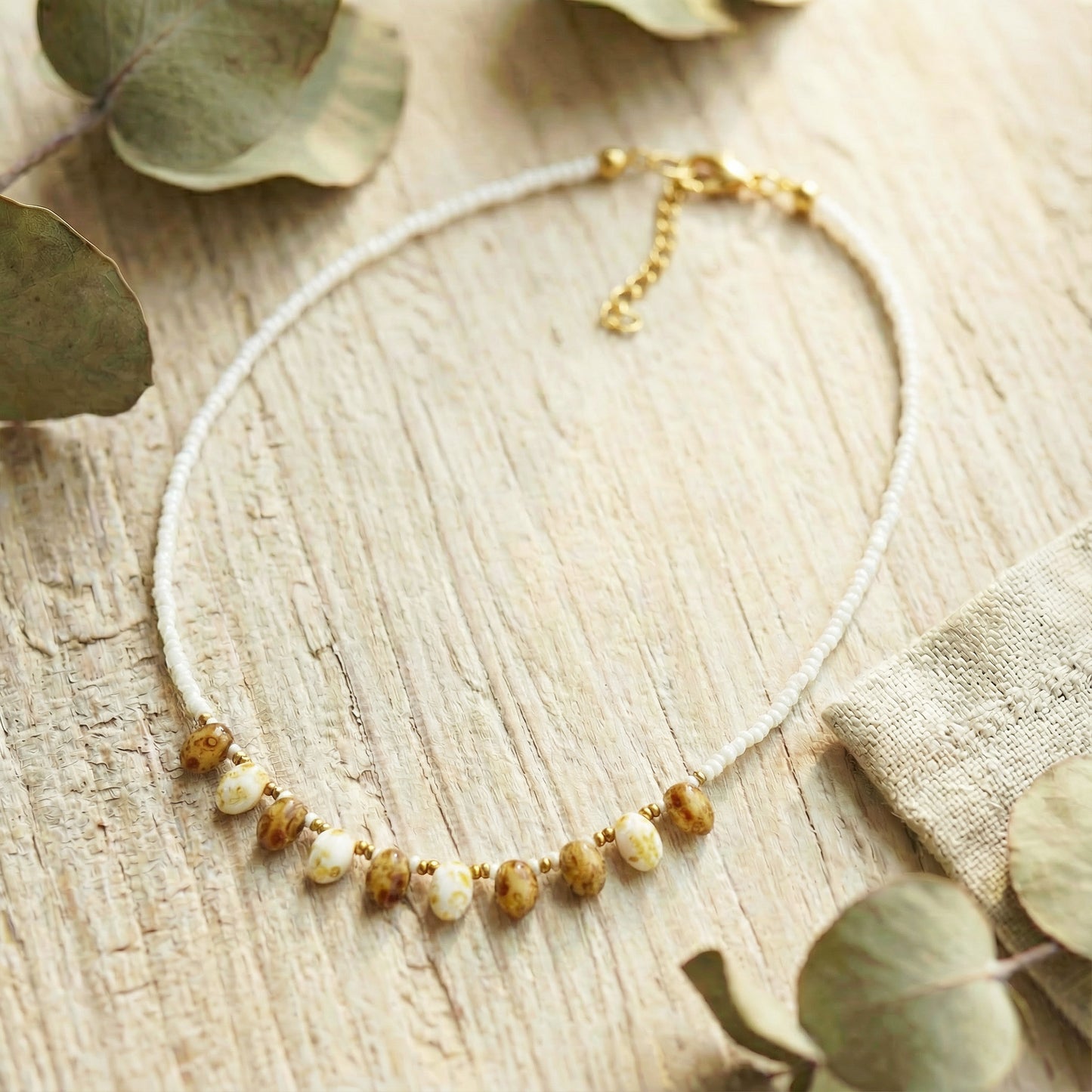 Necklace with beads on a wooden surface with eucalyptus leaves