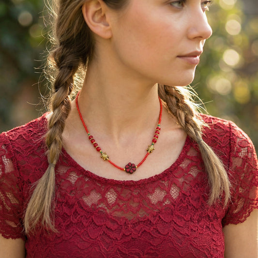 Woman wearing a red lace top and necklace with a blurred green background