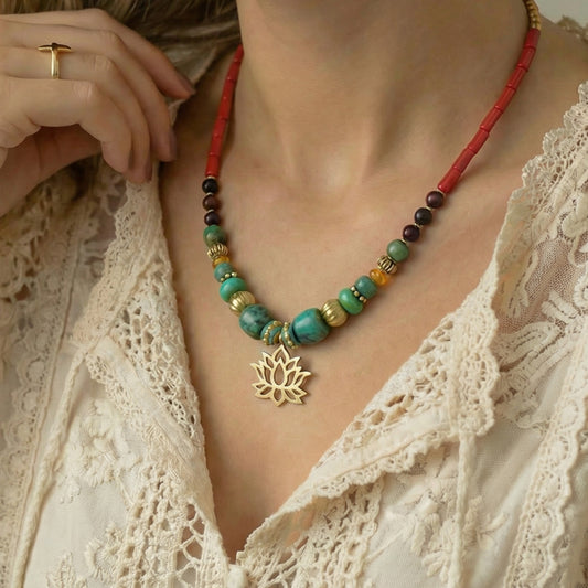 Necklace with colorful beads and a gold lotus pendant worn by a person in a white lace top.