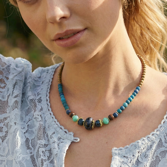 Close-up of a woman wearing a beaded necklace with a blurred natural background