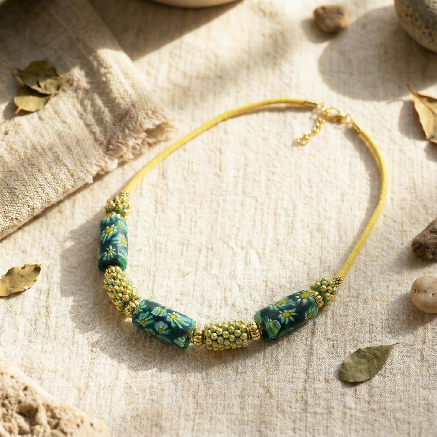 Necklace with floral beads on a textured surface with leaves and stones