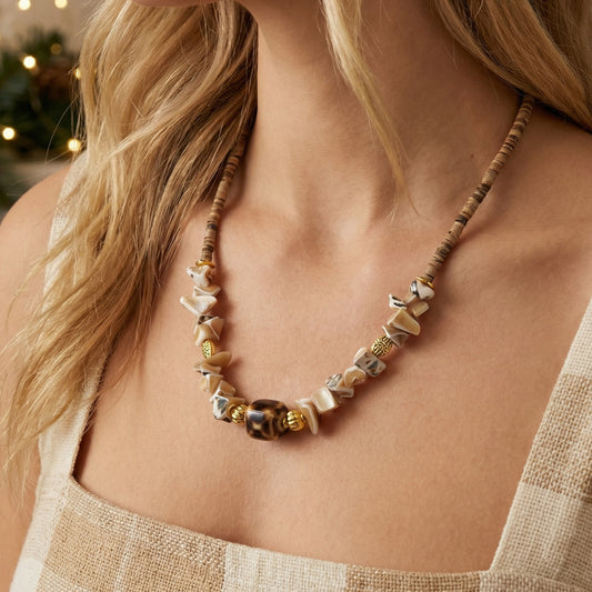 Necklace with natural stones and gold accents worn by a person with blurred background