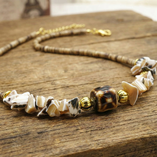 Necklace with shell and gold beads on a wooden surface