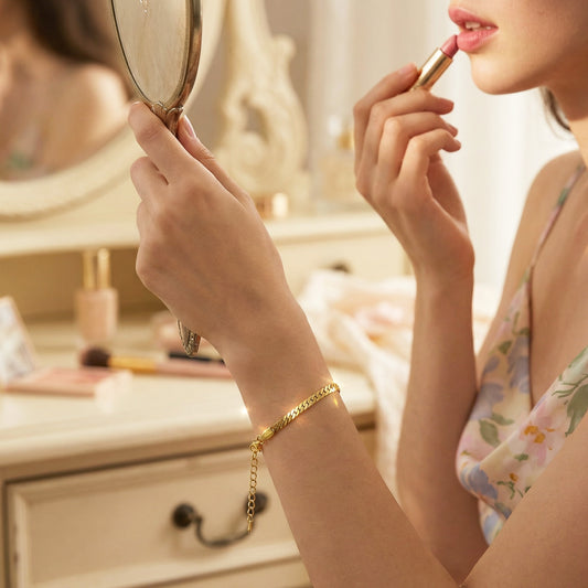 Woman applying lipstick in front of a mirror with a blurred background