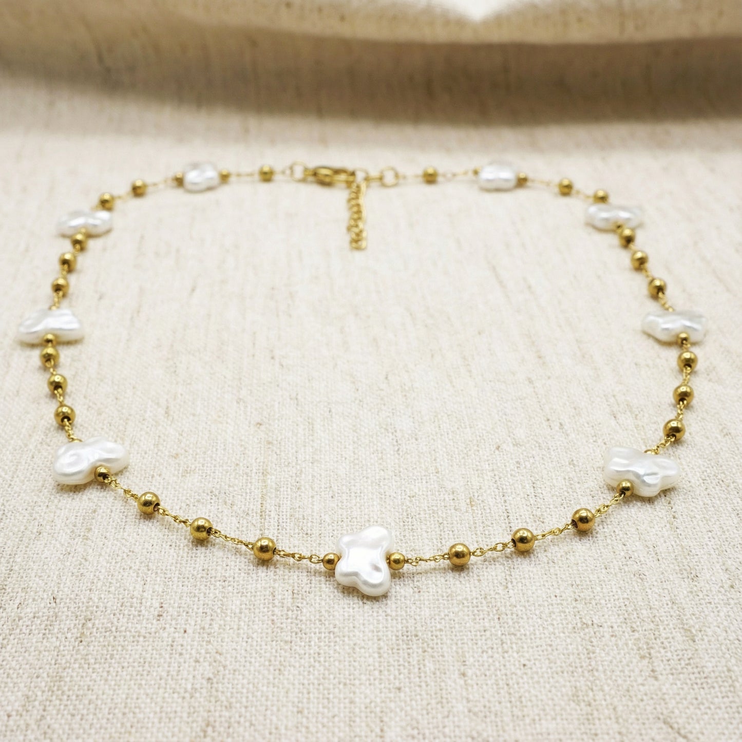 Gold bracelet with pearls on a beige fabric background