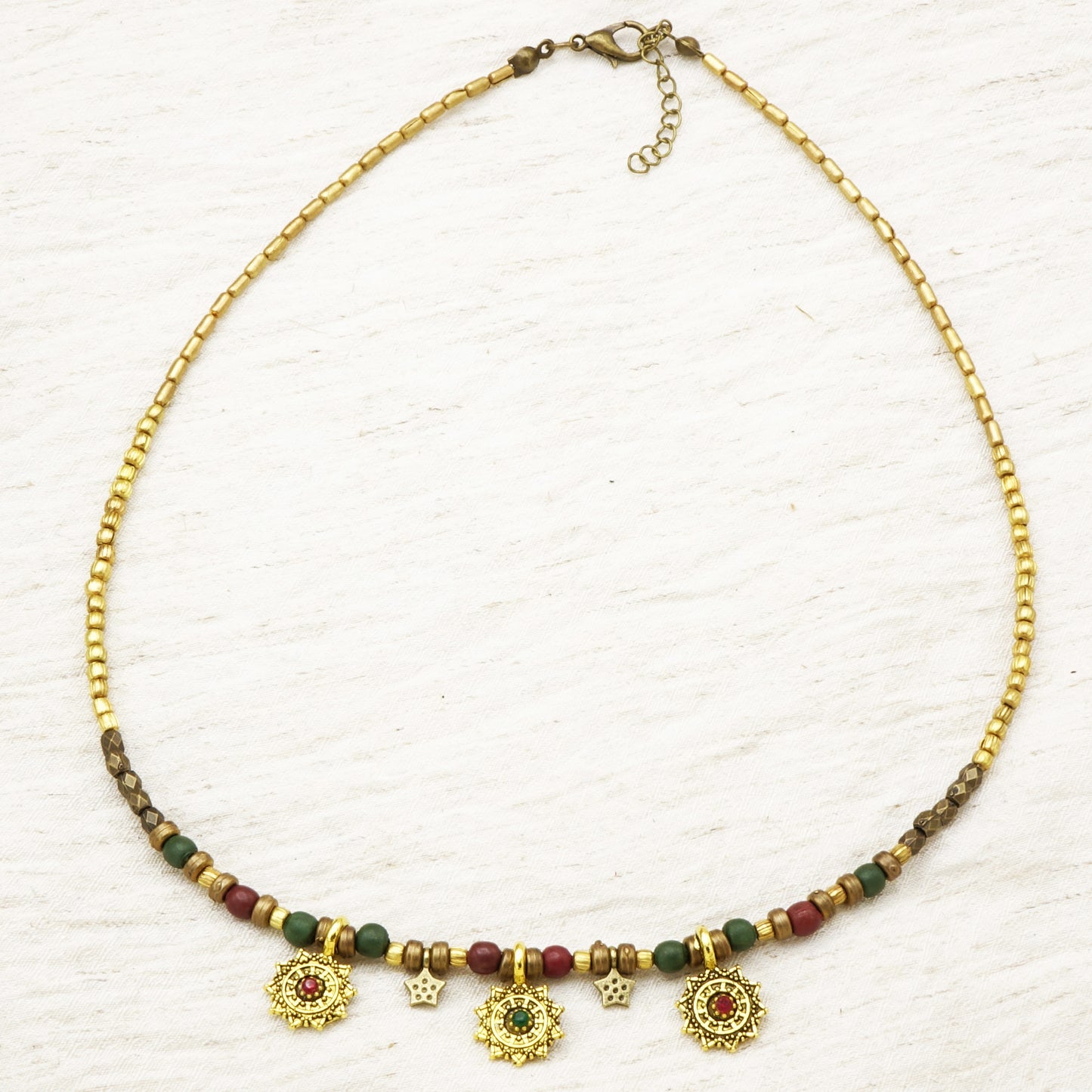 Necklace with gold chain, green and red beads on a white background