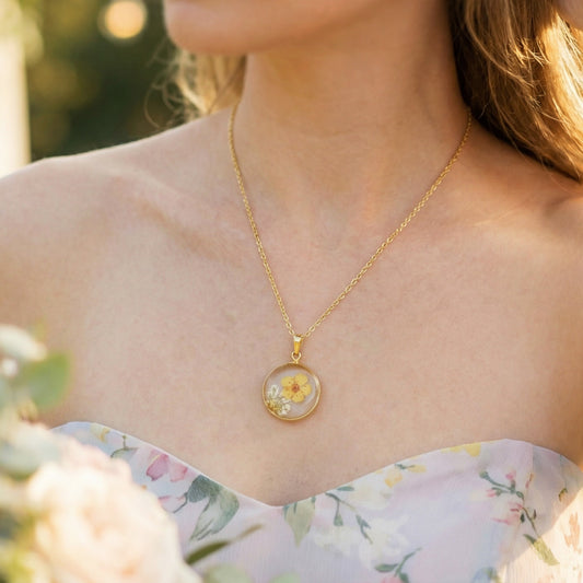 Woman wearing a gold necklace with a floral pendant outdoors