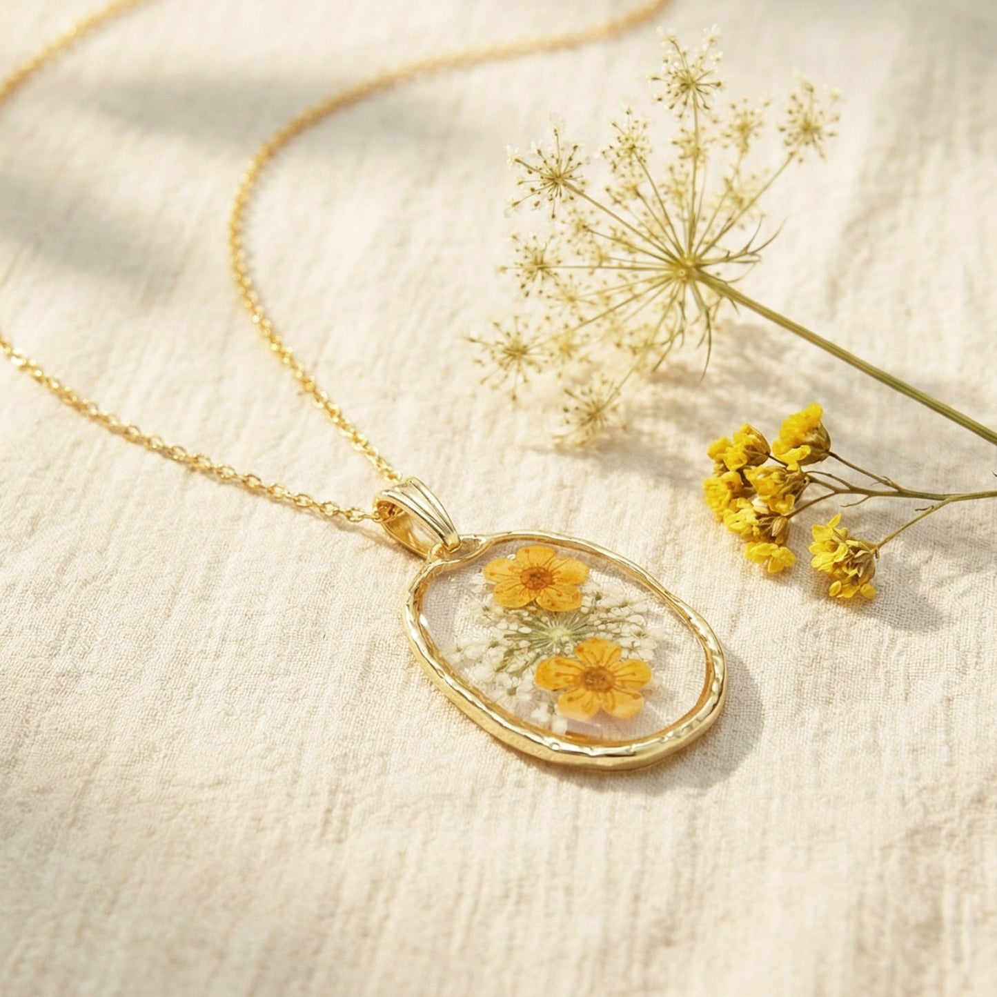 Gold necklace with a pendant featuring yellow flowers on a beige background