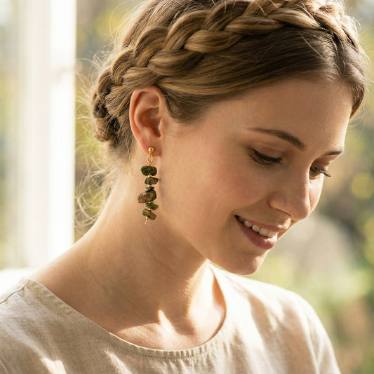 Woman with braided hair wearing green earrings outdoors