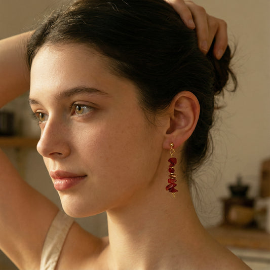 Close-up of a woman wearing red earrings with a blurred indoor background
