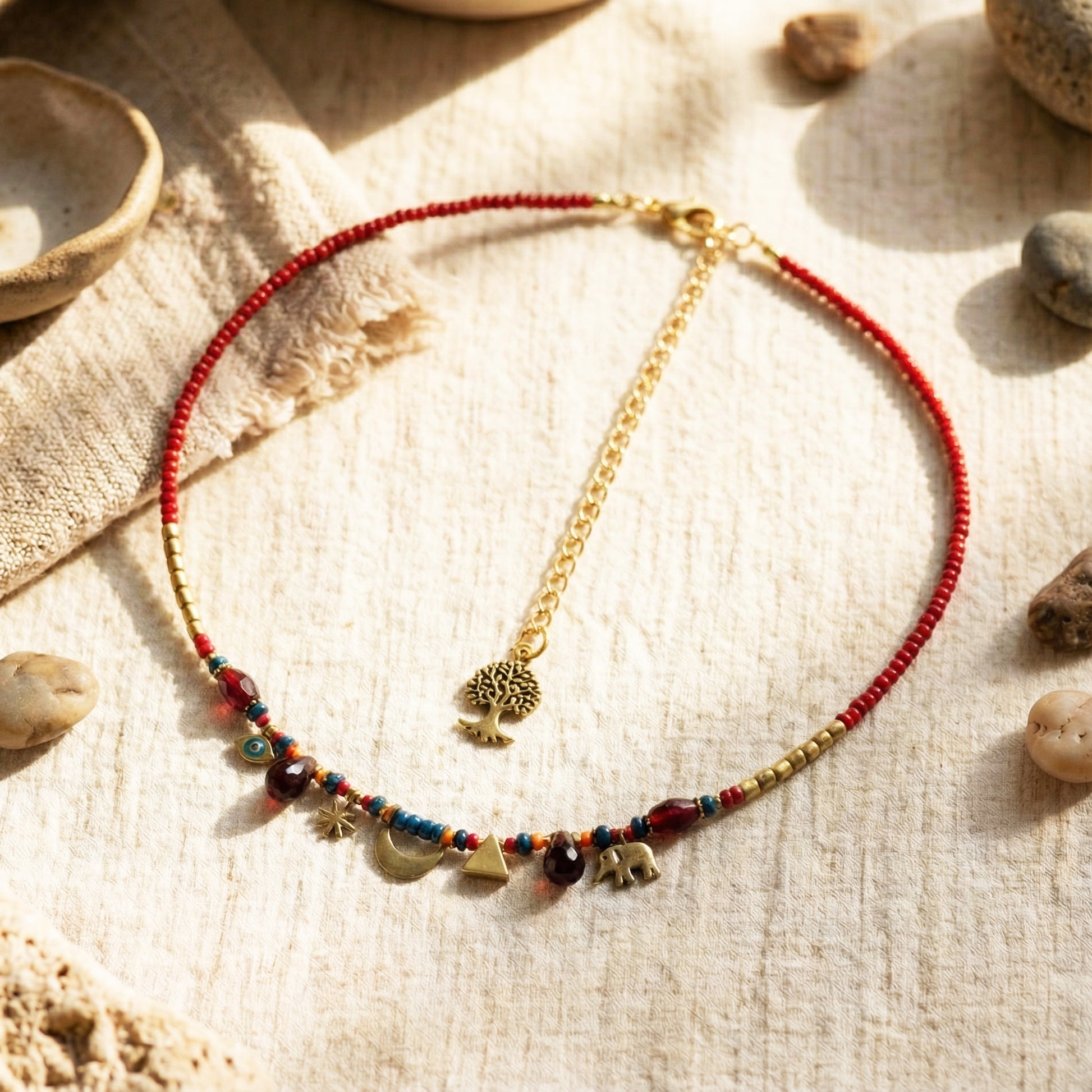 Necklace with red beads and gold chain on a textured surface with stones
