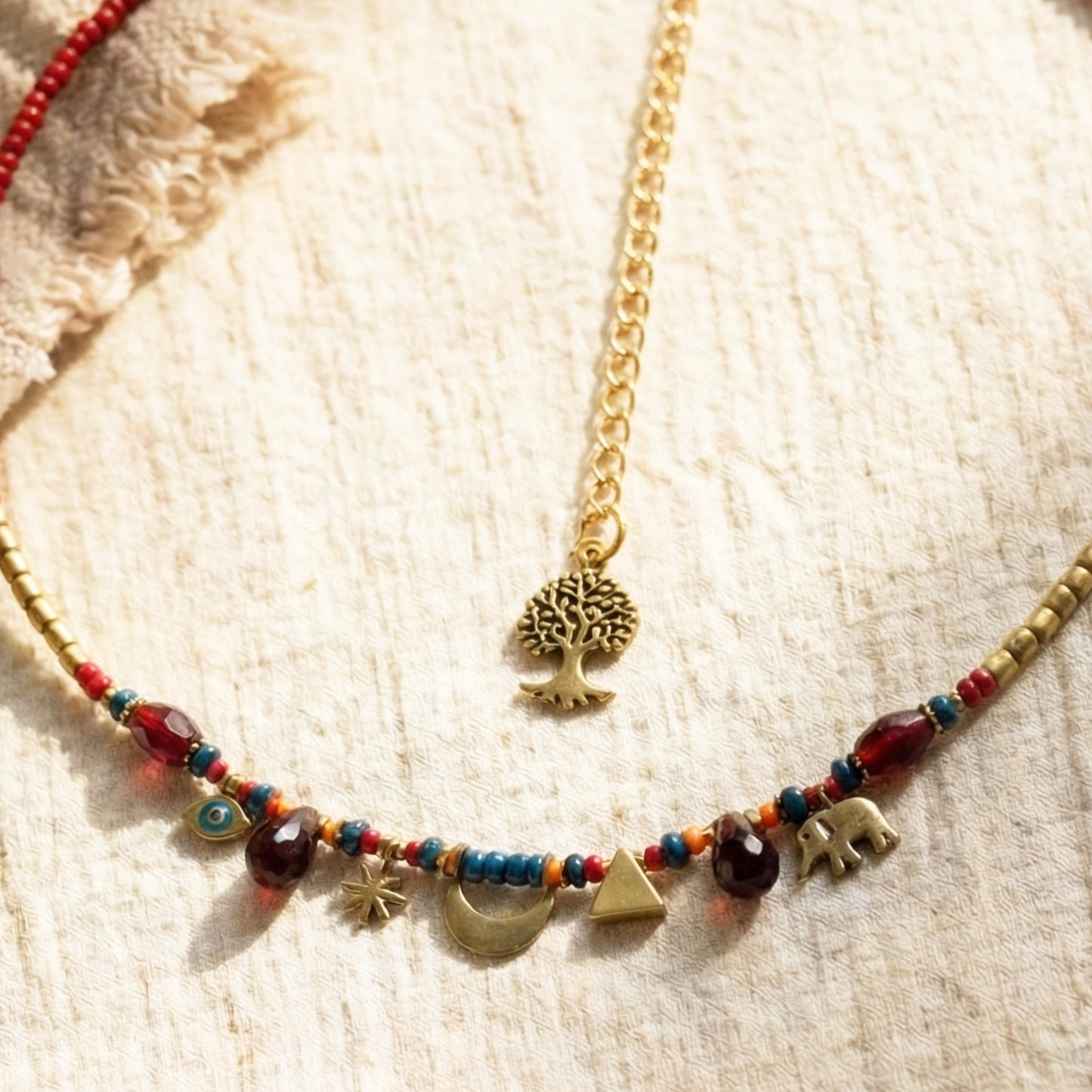 Necklace with colorful beads and gold charms on a textured beige surface