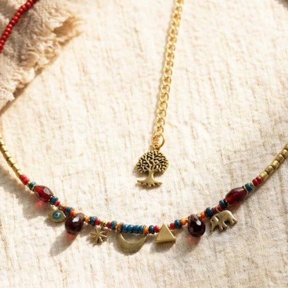 Necklace with colorful beads and gold charms on a textured beige surface