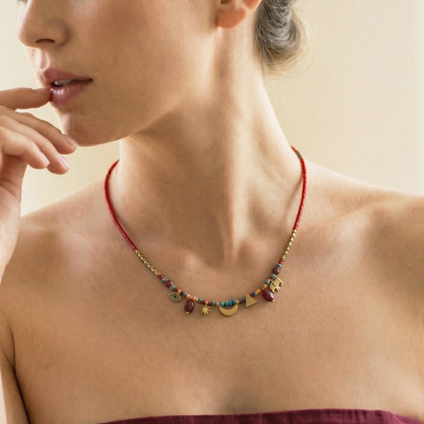 Woman wearing a colorful beaded necklace with a neutral background