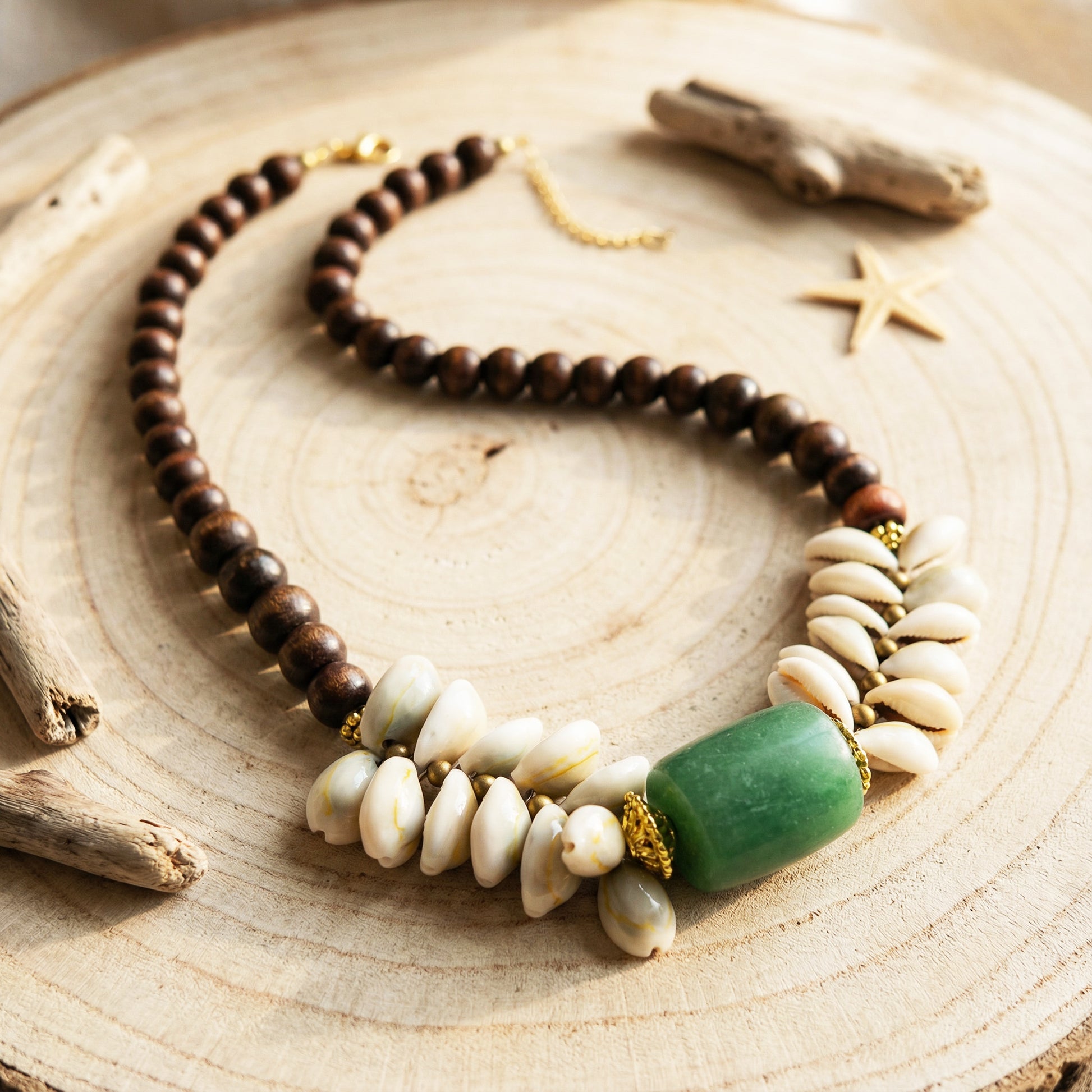 Necklace with wooden, shell, and green stone beads on a wooden surface.