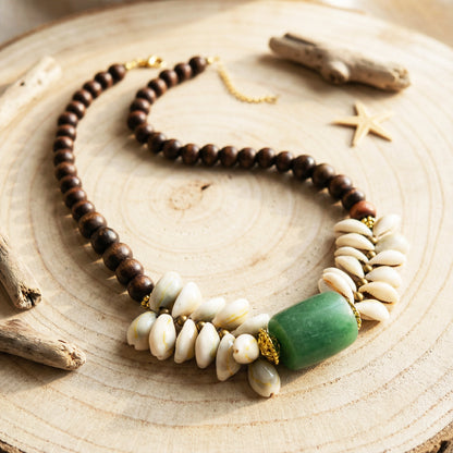 Necklace with wooden, shell, and green stone beads on a wooden surface.