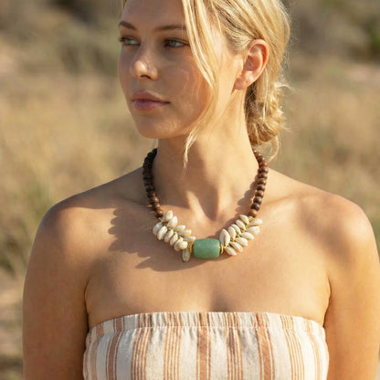 Woman wearing a beaded necklace with a blurred natural background