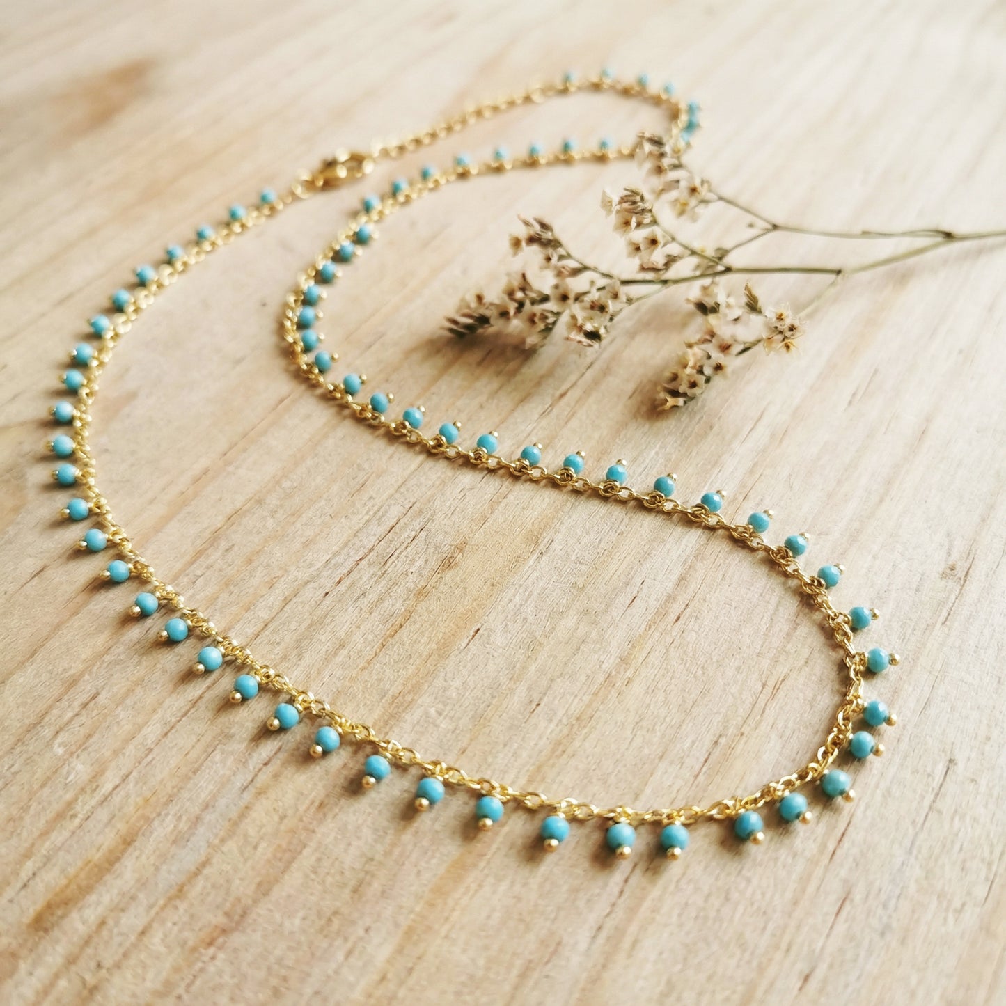 Gold necklace with turquoise beads on a wooden surface