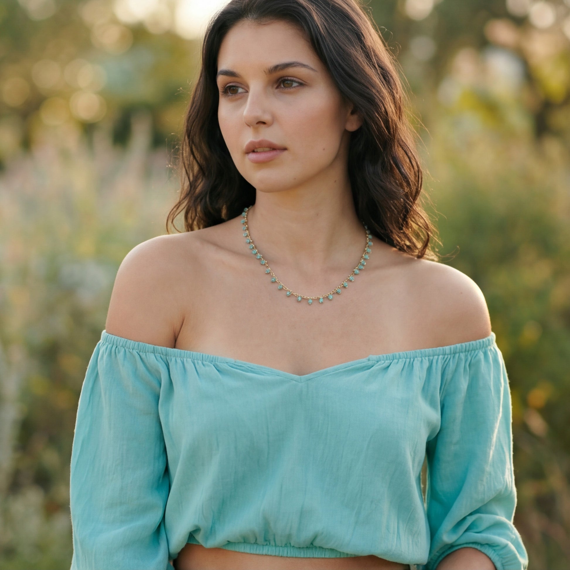 Woman wearing a light blue off-shoulder top with a blurred natural background