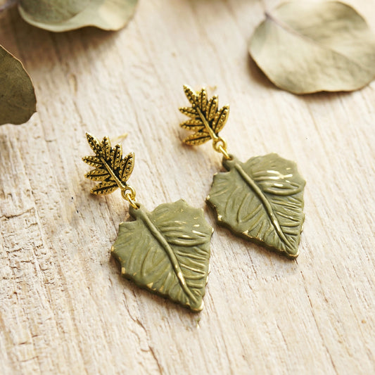 Pair of leaf-shaped earrings on a wooden surface