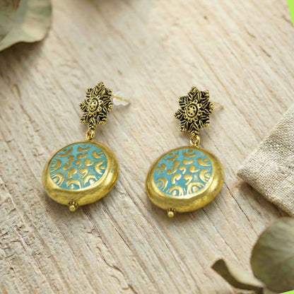 Pair of gold and turquoise earrings on a wooden surface
