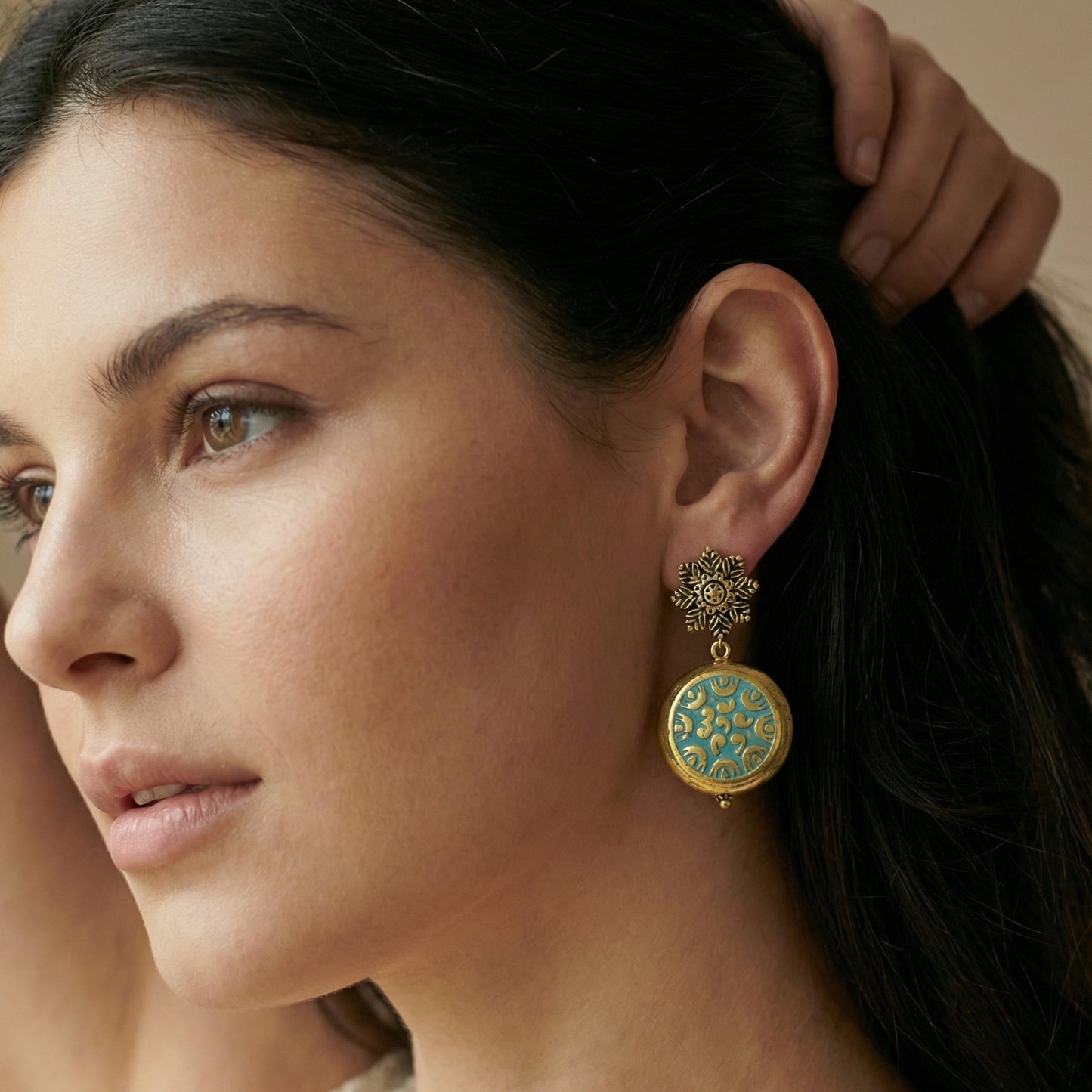 Close-up of a woman wearing a decorative earring with intricate design.