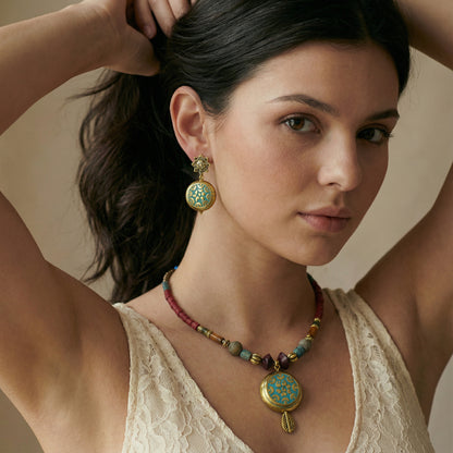 Woman wearing a necklace with a large pendant against a neutral background