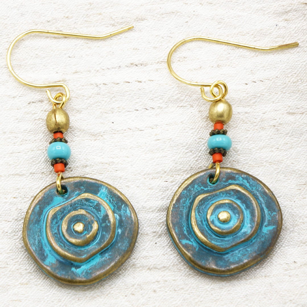 Pair of blue and gold spiral earrings on a textured white background