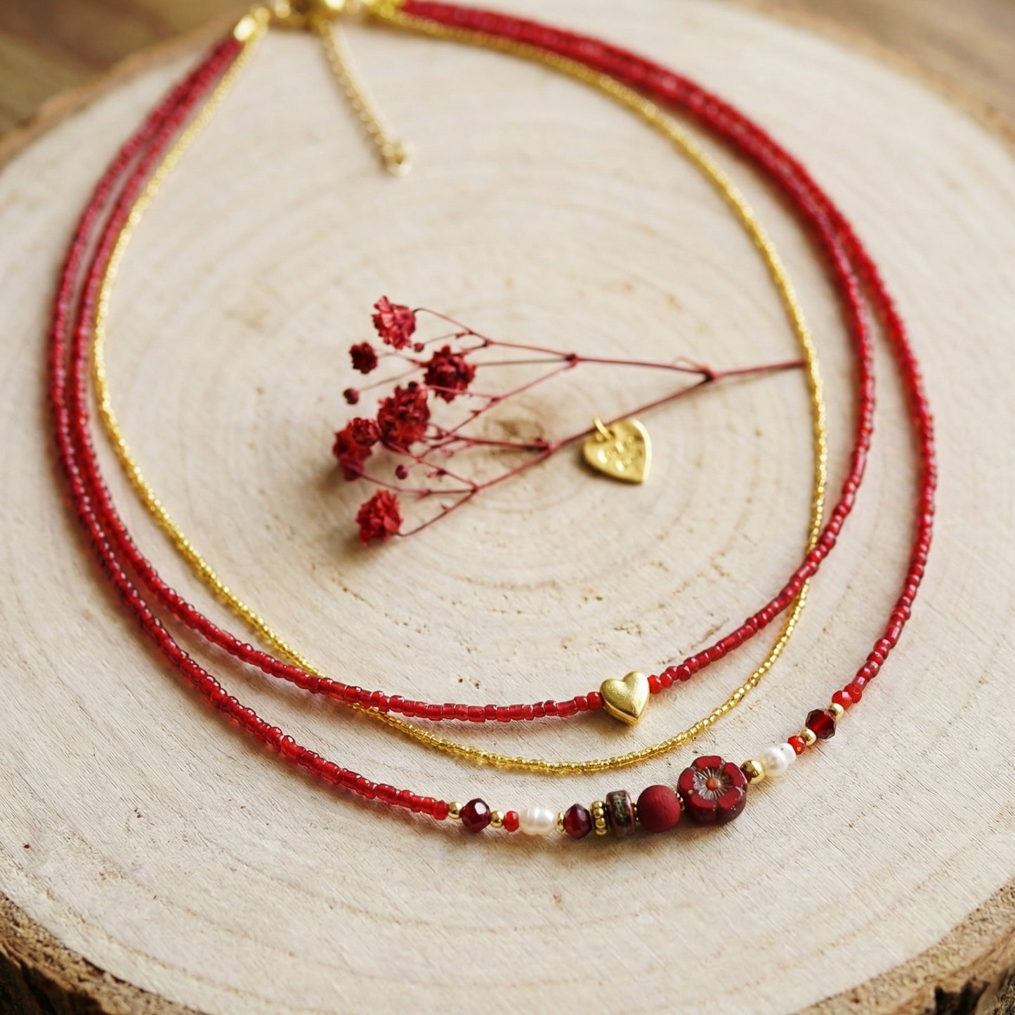 Layered necklace with red and gold beads on a wooden surface