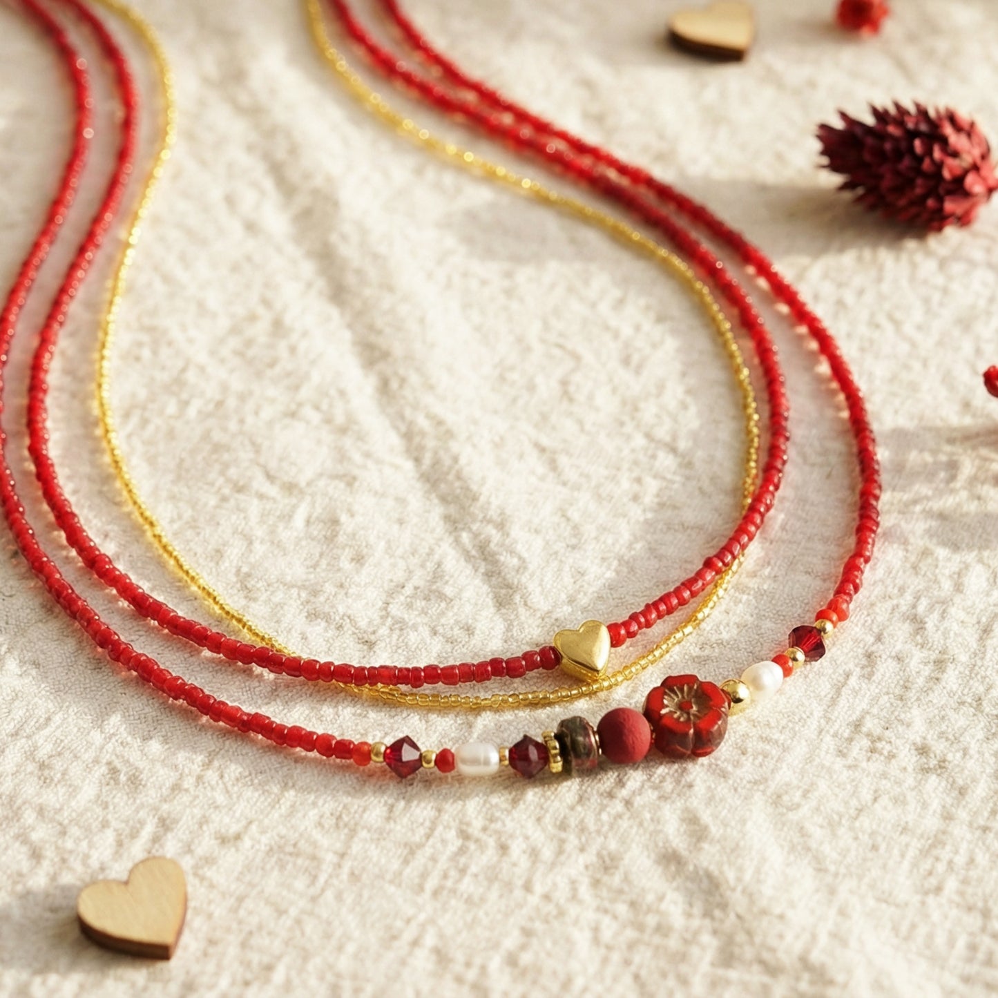 Red beaded necklace with gold accents on a textured white surface.