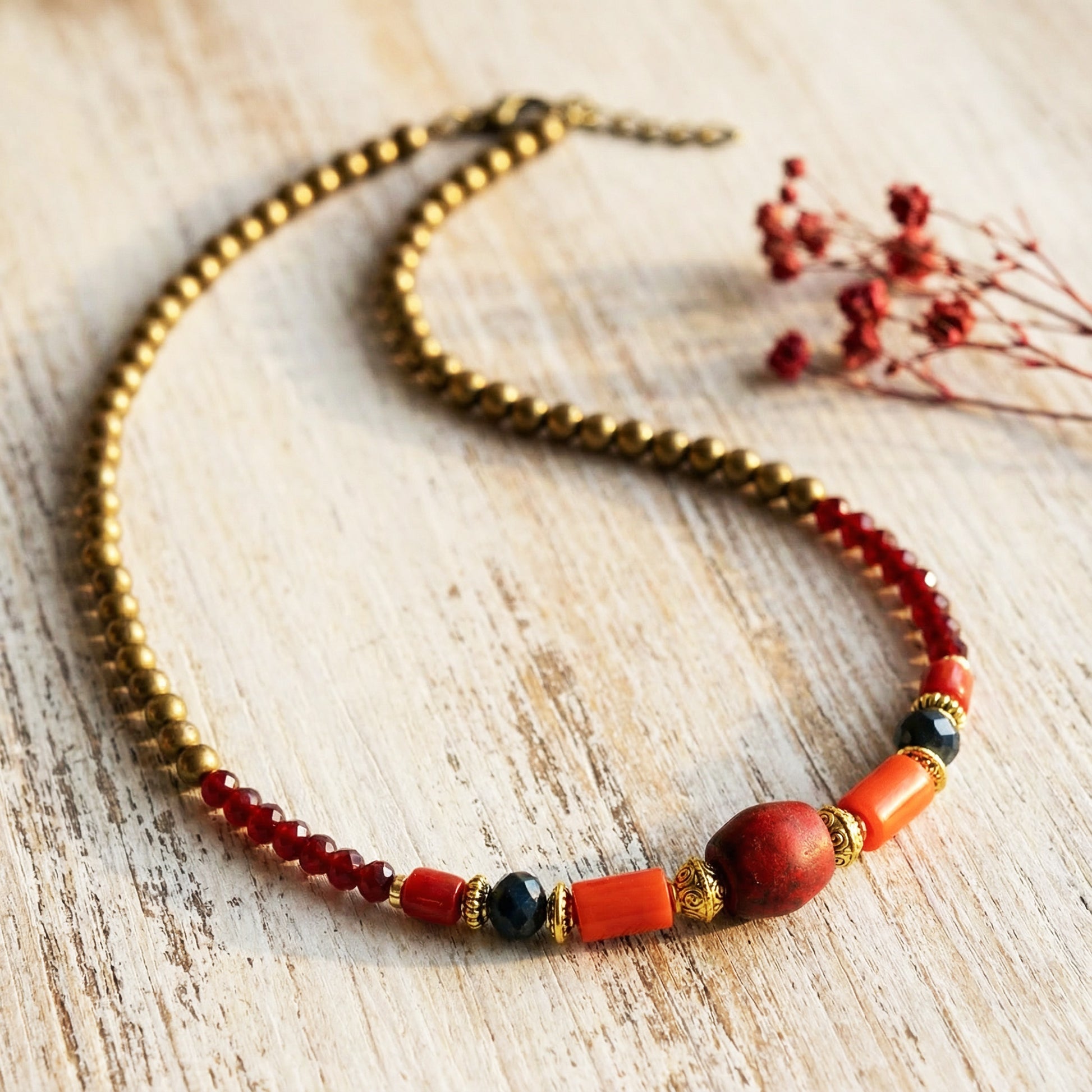 Beaded necklace with red, black, and gold beads on a wooden surface