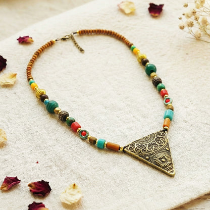 Colorful beaded necklace with a decorative triangle pendant on a light background