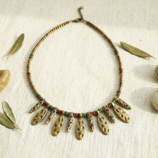 Necklace with leaf-like pendants and beads on a textured surface with leaves