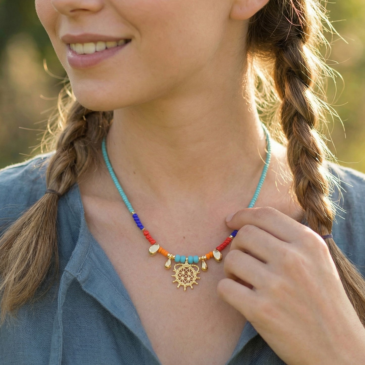 Woman wearing a colorful beaded necklace with a gold pendant outdoors