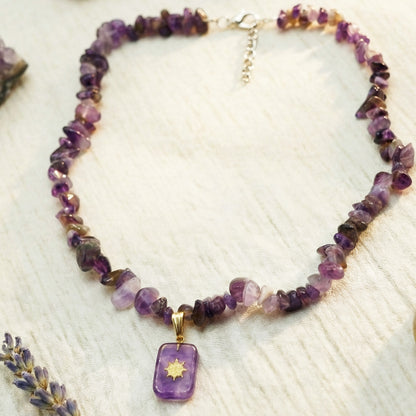 Necklace with purple beads and a pendant on a textured surface