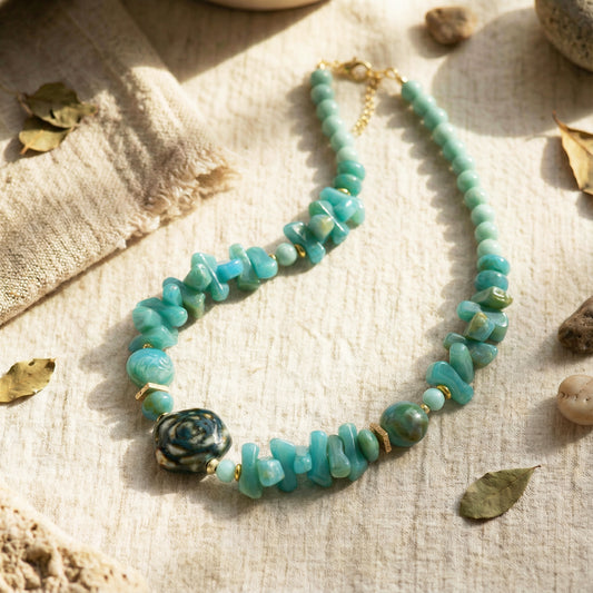 Turquoise beaded necklace on a textured surface with leaves and stones