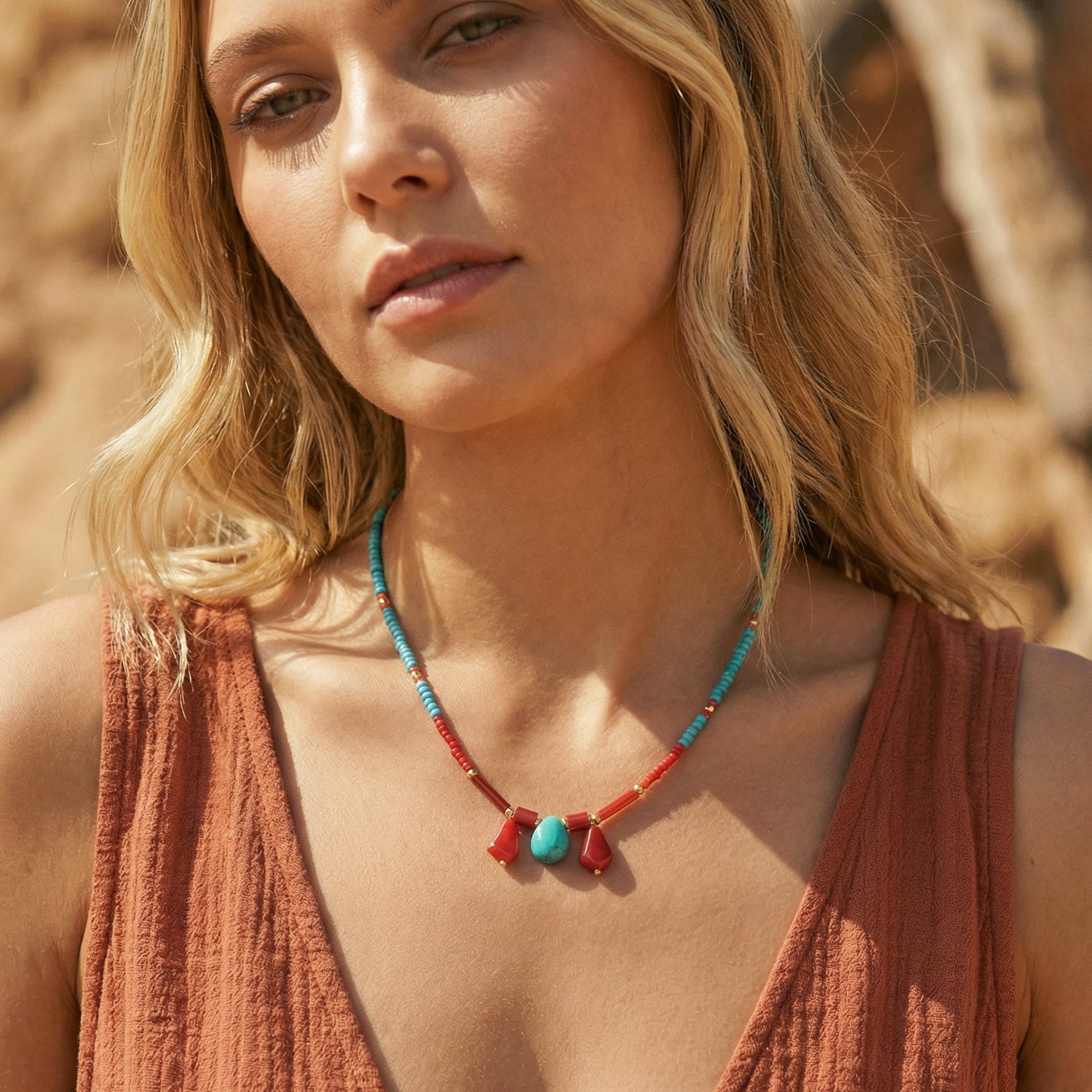 Woman wearing a necklace with turquoise and red beads against a blurred natural background