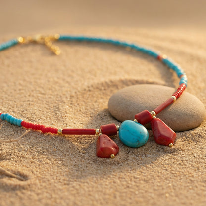 Necklace with red and blue beads on a sandy surface