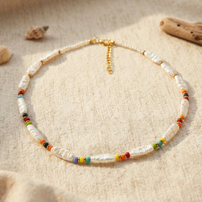 Necklace with pearls and colorful beads on a sandy background