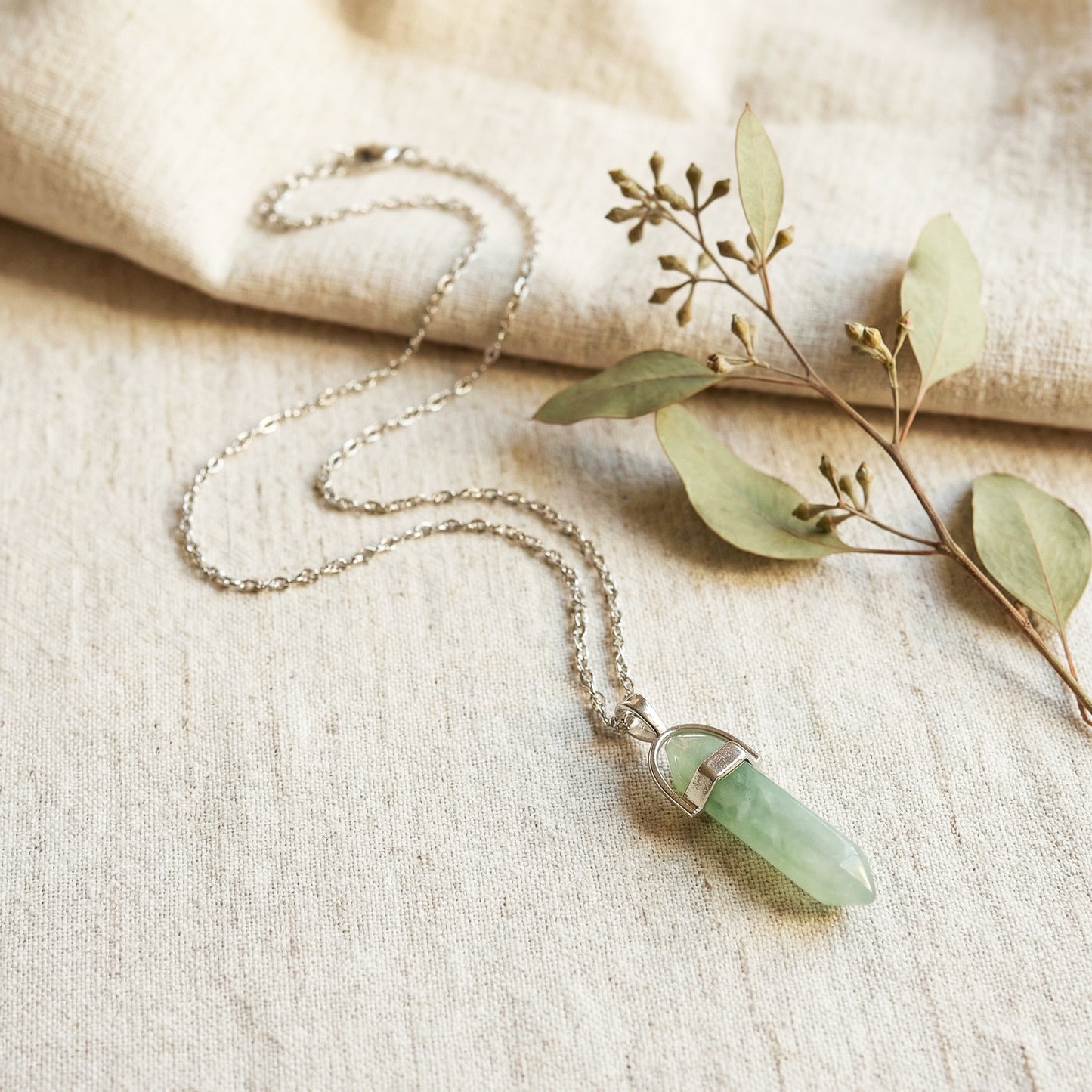 Necklace with a green pendant on a beige fabric background