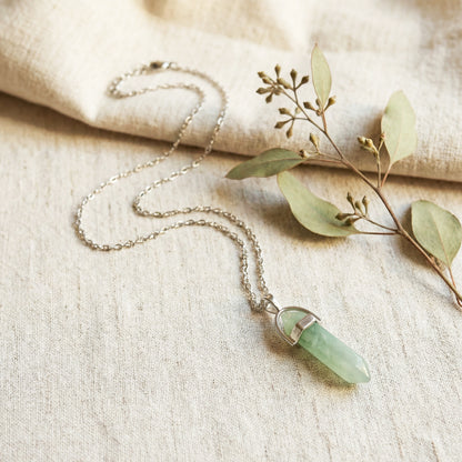 Necklace with a green pendant on a beige fabric background