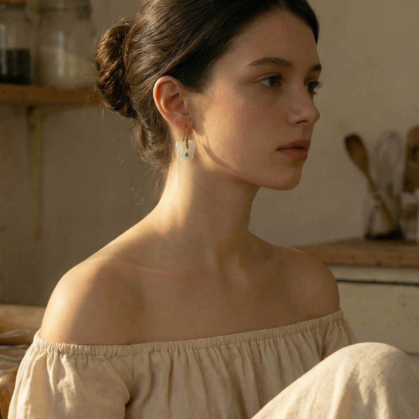 Woman wearing a beige off-shoulder top in a warm-toned kitchen setting