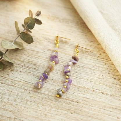 Pair of beaded earrings on a textured surface with green leaves