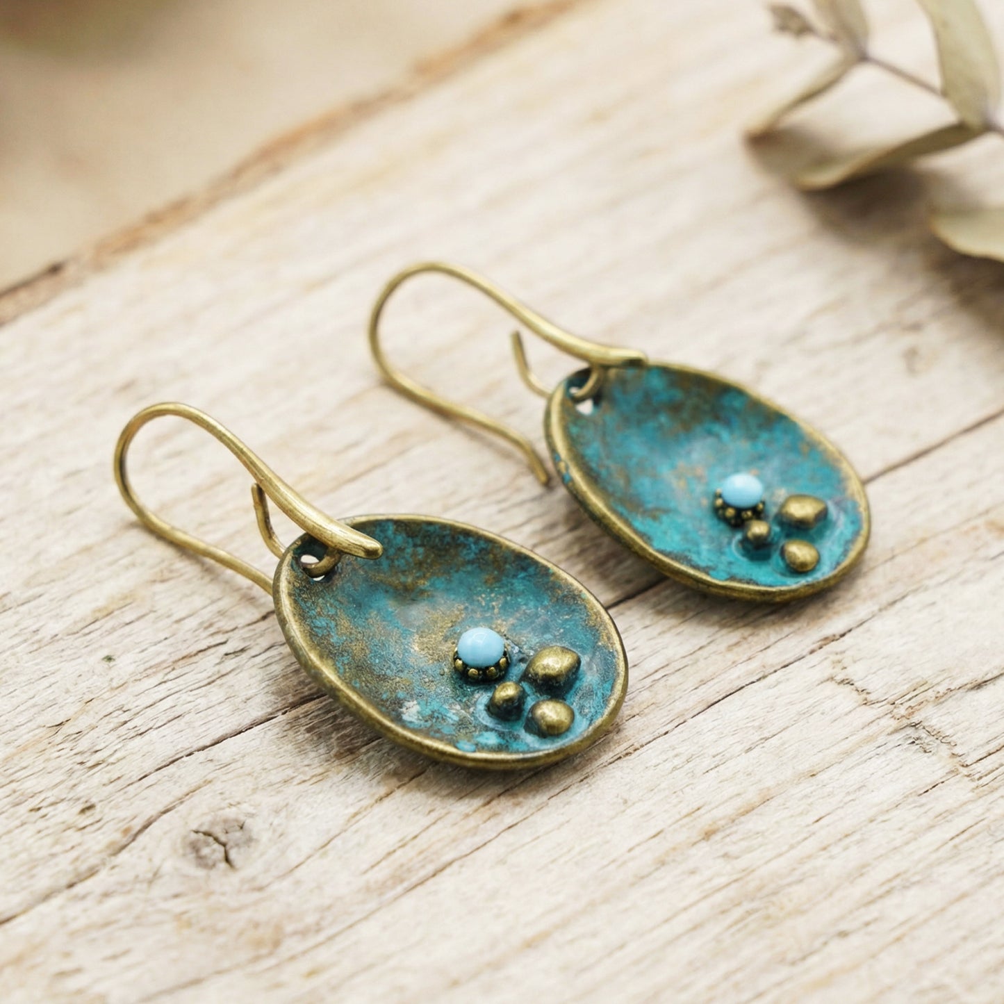 Pair of earrings with blue and gold accents on a wooden surface