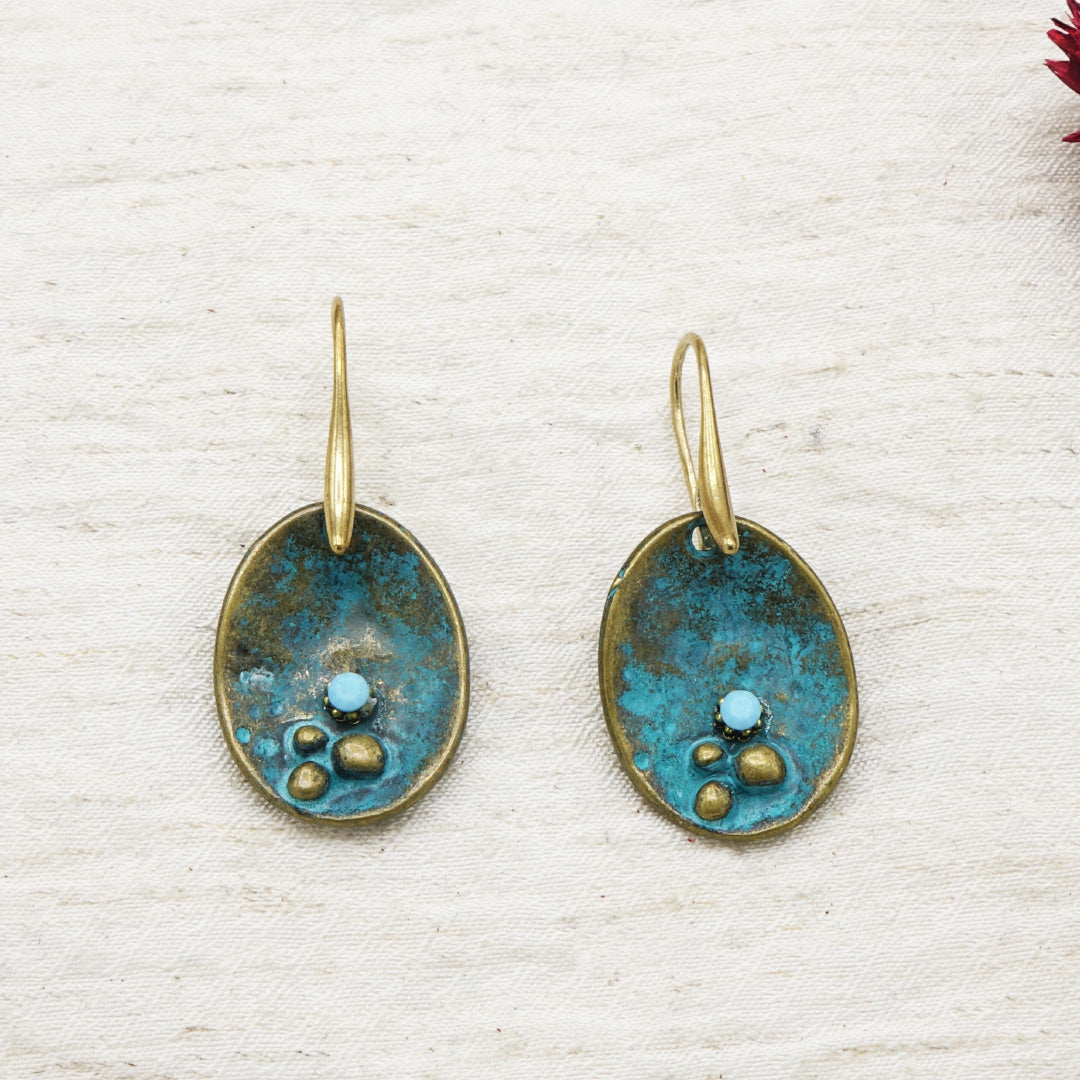 Pair of earrings with blue and gold design on a textured white background